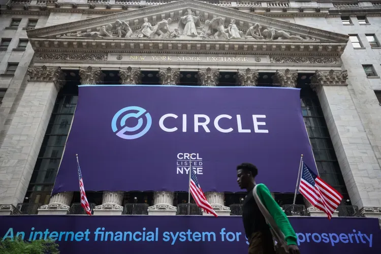 شعار الدائرة معروض في بورصة نيويورك خلال إدراج شركة CRCL، مع وجود أعلام ومشاة في المقدمة.